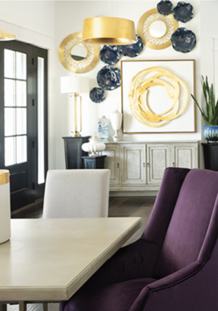 about you featured image of a lambs interior designed room. The room has a purple chair, table, framed artwork and gold/black decor.